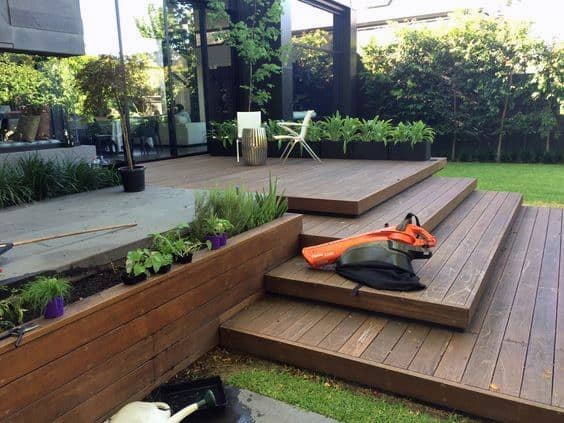 Tiered wooden deck with built-in planters, steps, and modern outdoor seating area.