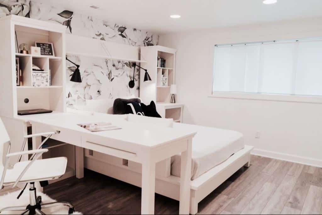 Modern white bedroom with platform bed, desk, and floral wallpaper accents.