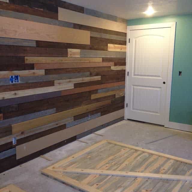 Basement room with multicolored wood paneling on the wall and white door for contrast.