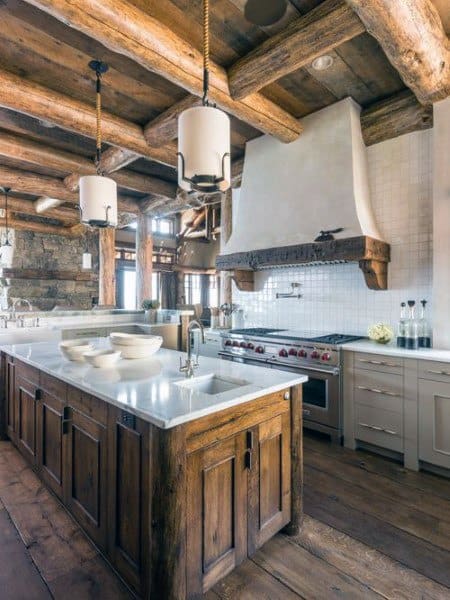 Rustic kitchen with log beam ceiling, wood island, white cabinets, and pendant lighting.