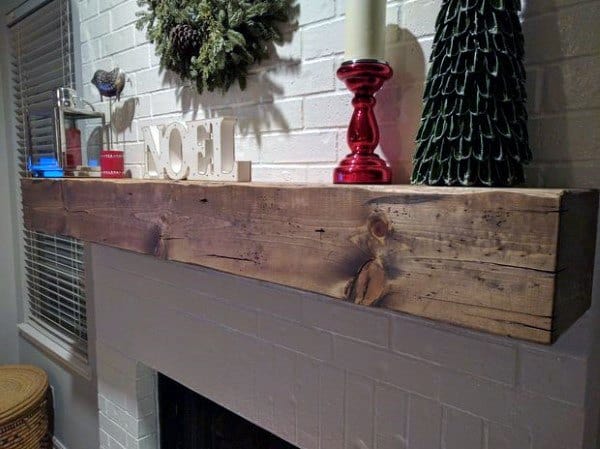 White painted brick fireplace with a thick, rustic wooden beam mantel featuring natural wood grain.