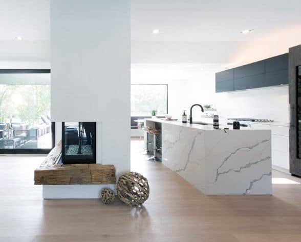 Modern kitchen with a double-sided fireplace, rustic wooden mantel, and marble countertops.