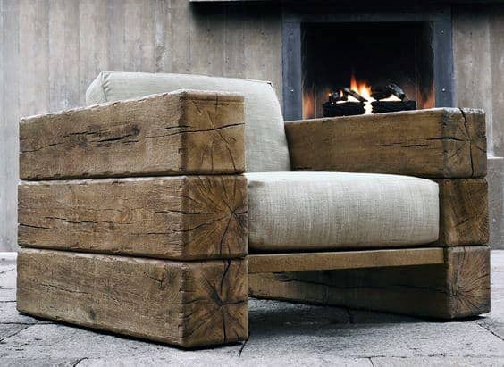 Rustic wooden armchair with a beige cushion, set in front of a lit fireplace