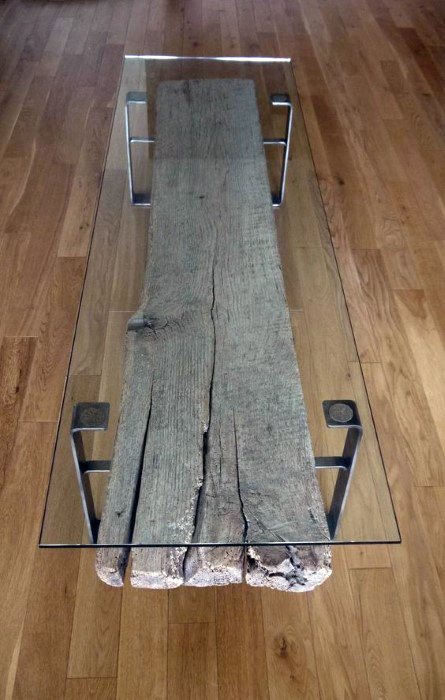 Rustic coffee table with reclaimed wood beam base and glass top.