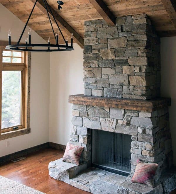 Rustic stone fireplace with a wooden mantle under a vaulted wood ceiling.