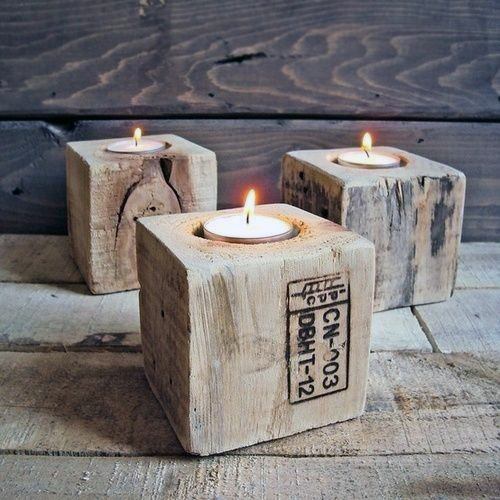 Three lit tea light candles in rustic wooden block holders on a wooden surface