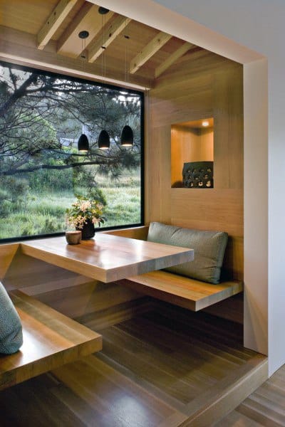 Cozy wooden nook with table by a window, overlooking greenery; modern pendant lights above
