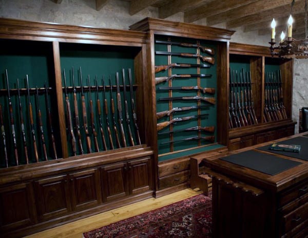 Gun room with dark wooden cabinets, green backing, and rifles displayed neatly on racks.
