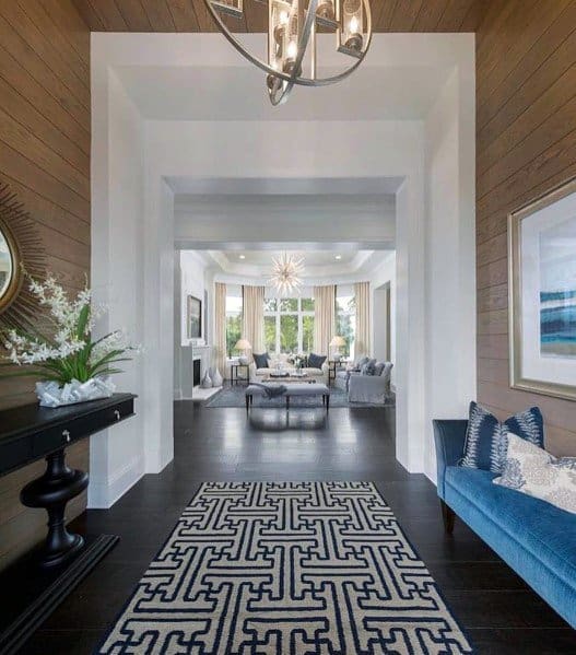 Contemporary entryway with wood ceiling and walls, blue bench, patterned rug, and decor accents.