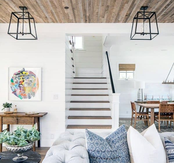 Bright living room with rustic wood ceiling, white shiplap walls, modern lantern lights, and cozy decor.
