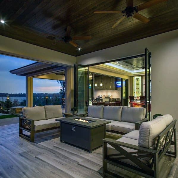 Outdoor patio with wood ceiling, cozy seating area, fire pit, and open kitchen.