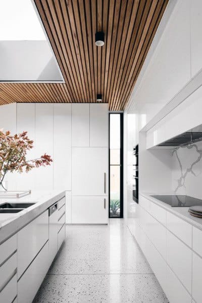 Ultra-modern kitchen with slatted wood ceiling, sleek white cabinets, and marble countertops.