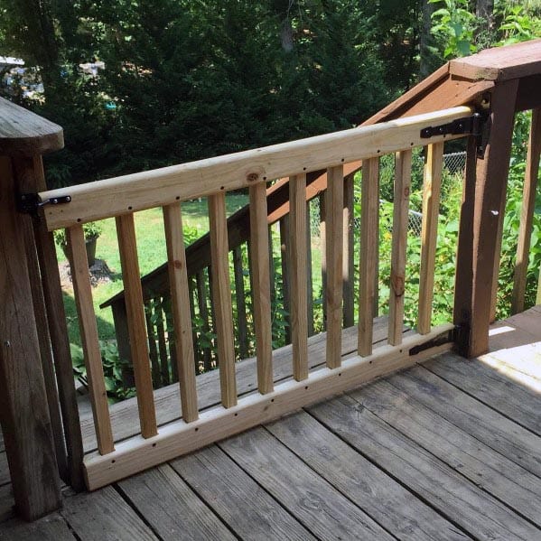 Deck gate at the top of outdoor stairs with greenery in the background