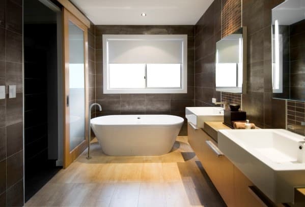Modern bathroom with a large bathtub, double sinks, wooden cabinets, and a large window