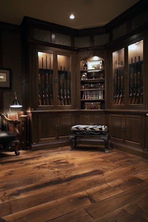 Elegant gun room with rich wooden flooring, dark cabinetry, and built-in displays for rifles and books.