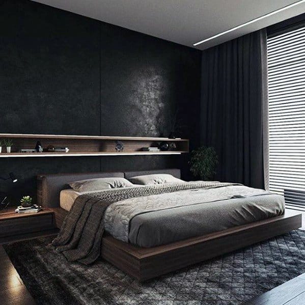 Modern bedroom with a low wooden platform bed, dark accent walls, and floating shelf decor.