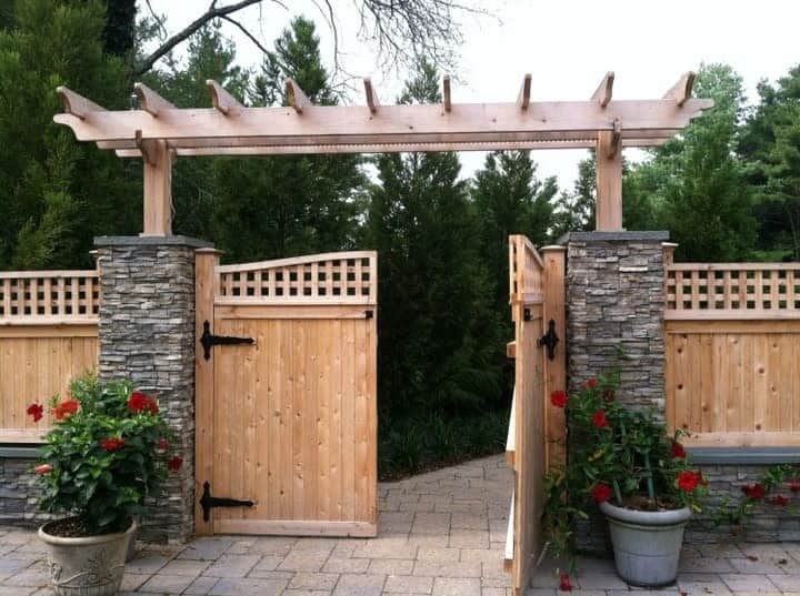 wood garden gate stone pillars red flowers in pot plants