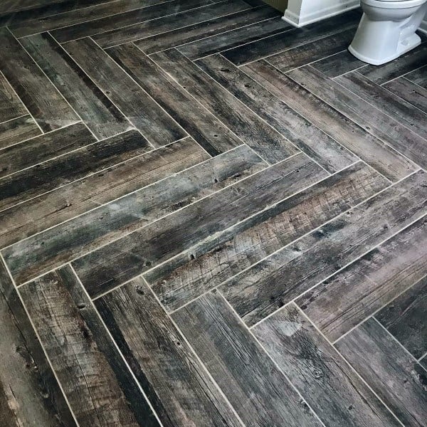 Herringbone-patterned wood-look floor tiles in a bathroom.