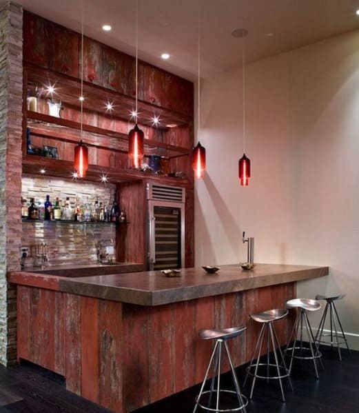 Modern bar with red pendant lights, wood paneling, metal stools, and a stocked shelf of various spirits