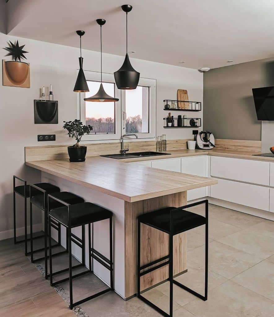 Modern kitchen with minimalist wood countertops, sleek black stools, and stylish pendant lighting.