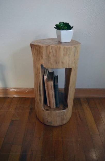 Wooden side table with a plant on top and books stored in a built-in shelf, placed on a wooden floor