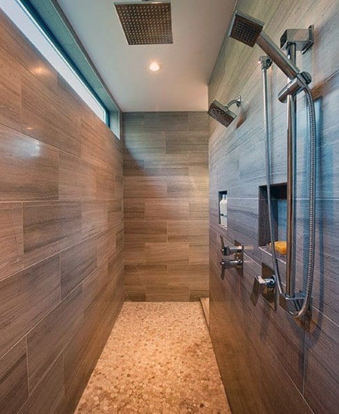 Modern shower with wooden-style tiles and dual showerheads, featuring a unique pebble stone floor