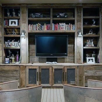 Rustic man cave with wood shelves, a TV, books, model cars, vintage decor, and angled chairs up front