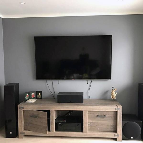 Wall-mounted flat screen TV with a rustic wooden media cabinet and surround sound speakers.