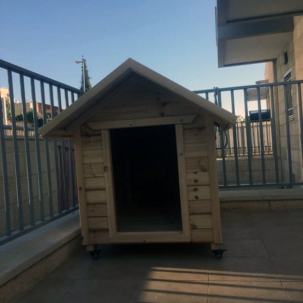 A simple wooden dog house made from planks, featuring a sloped roof
