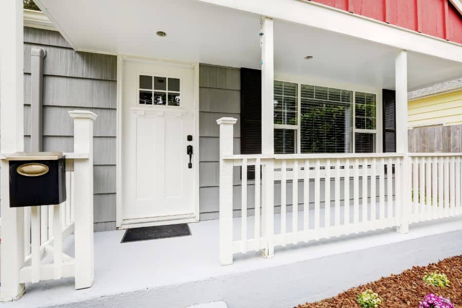 farmhouse home with wood porch white railing 