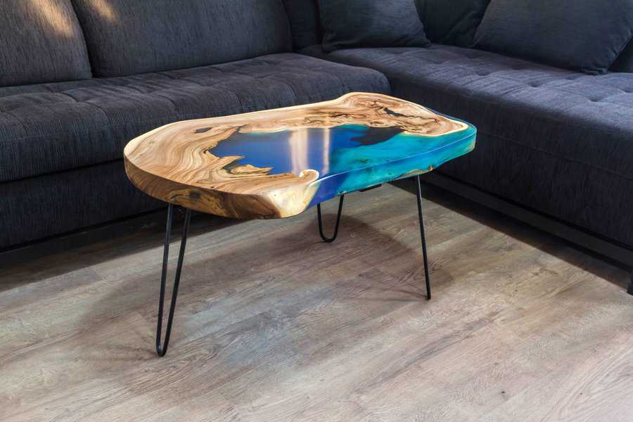 Natural wood slab coffee table with blue resin inlay and metal legs in a modern living room.