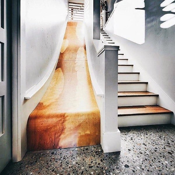 A wooden slide playfully complements the staircase in this modern home interior