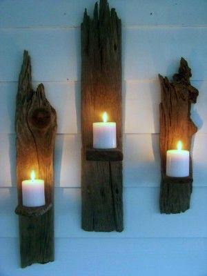 Rustic wooden candle holders mounted on the wall with lit white candles.