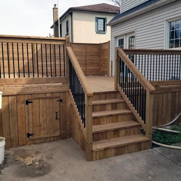 large wood deck with black metal balusters and wood railing and skirting