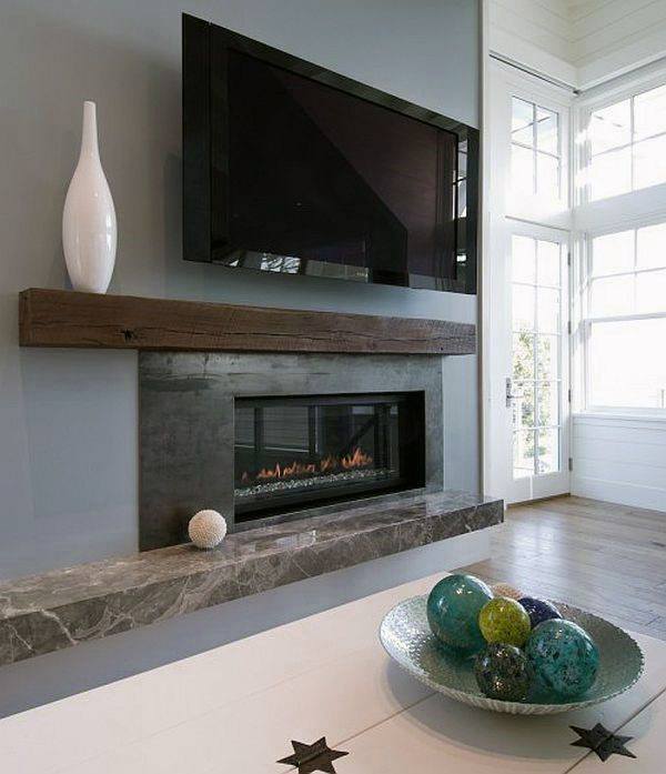 Contemporary gas fireplace with a dark marble base, rustic wooden mantel, and a mounted TV for a modern living room ambiance.
