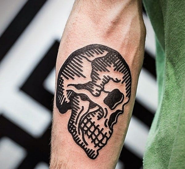 Forearm tattoo of a black, abstract skull with bold lines and shading