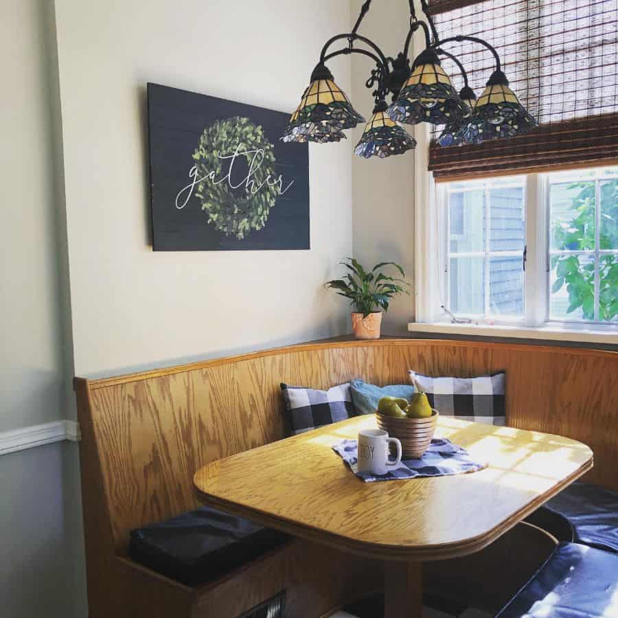 Cozy wooden banquette seating with a decorative sign, plaid pillows, and a warm pendant light.