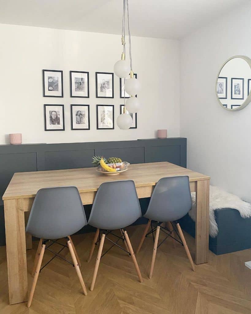 Modern dining area with wooden table, grey chairs, and gallery wall of black-framed photos.