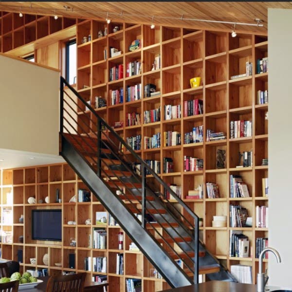 Modern room with a large wooden bookshelf, staircase, and a ceiling with exposed beams
