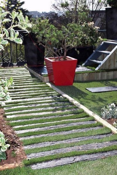 Walkway with stone steps, a red potted plant, and neatly trimmed grass