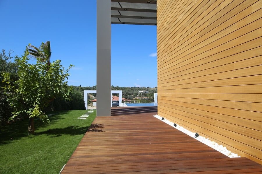 Modern wooden deck with a tree, walkway, and distant landscape under a clear blue sky