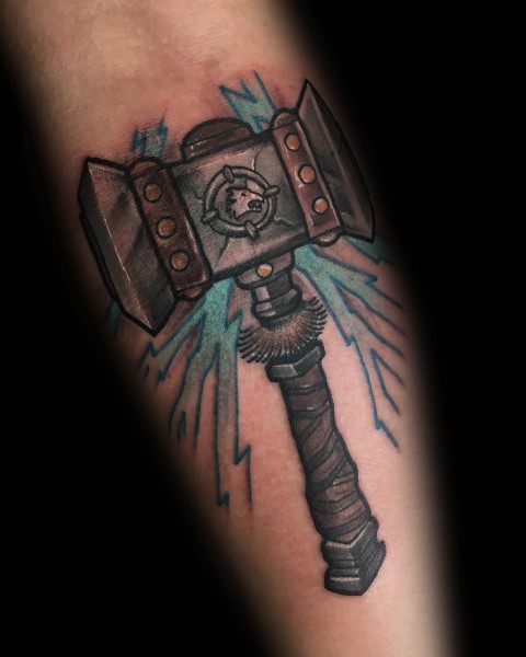 Tattoo of Doomhammer from World of Warcraft, featuring bold shading, intricate details, and blue lightning effects, inked on the forearm.