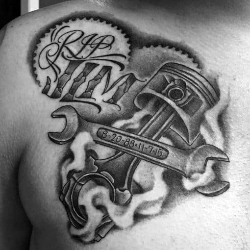 Black and grey chest tattoo featuring a wrench and piston with engraved dates, surrounded by smoke, gears, and the tribute text RIP JIM.