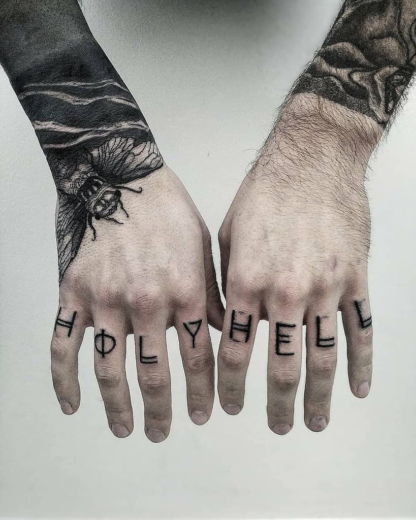 Black cicada tattoo on the hand with bold shading extending to the wrist, paired with 'HOLY HELL' lettering on the fingers