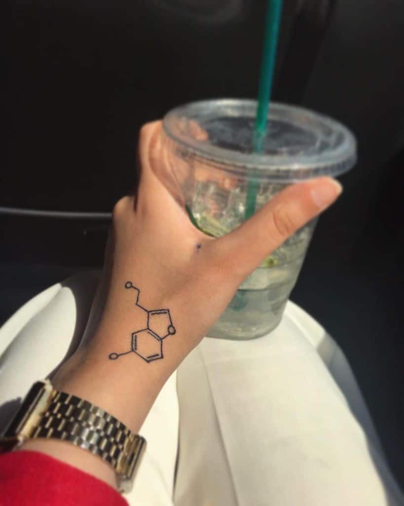 Simple serotonin molecule tattoo on the wrist, symbolizing happiness and positivity