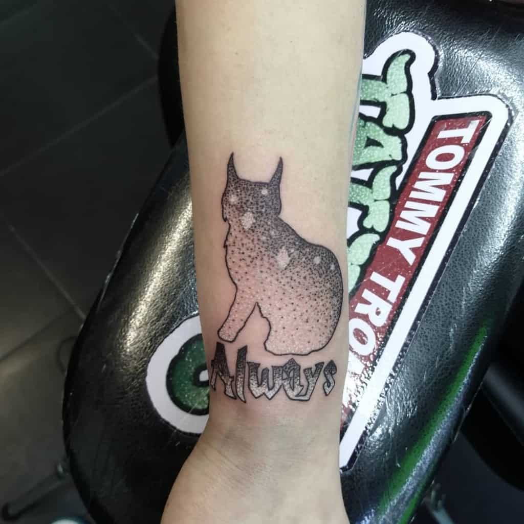 Harry Potter-inspired tattoo of a cat silhouette with starry details and 'Always' in bold script on the wrist