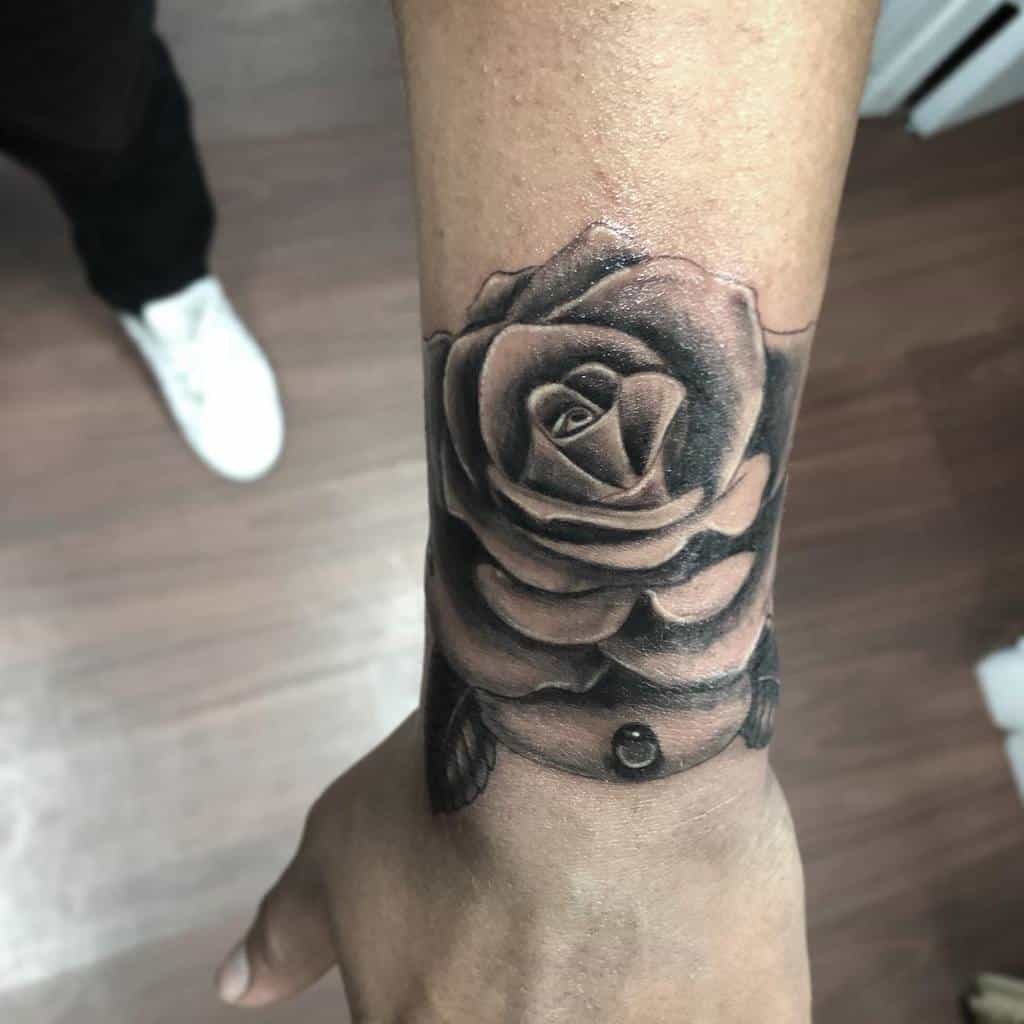 A detailed black and gray rose tattoo on a wrist