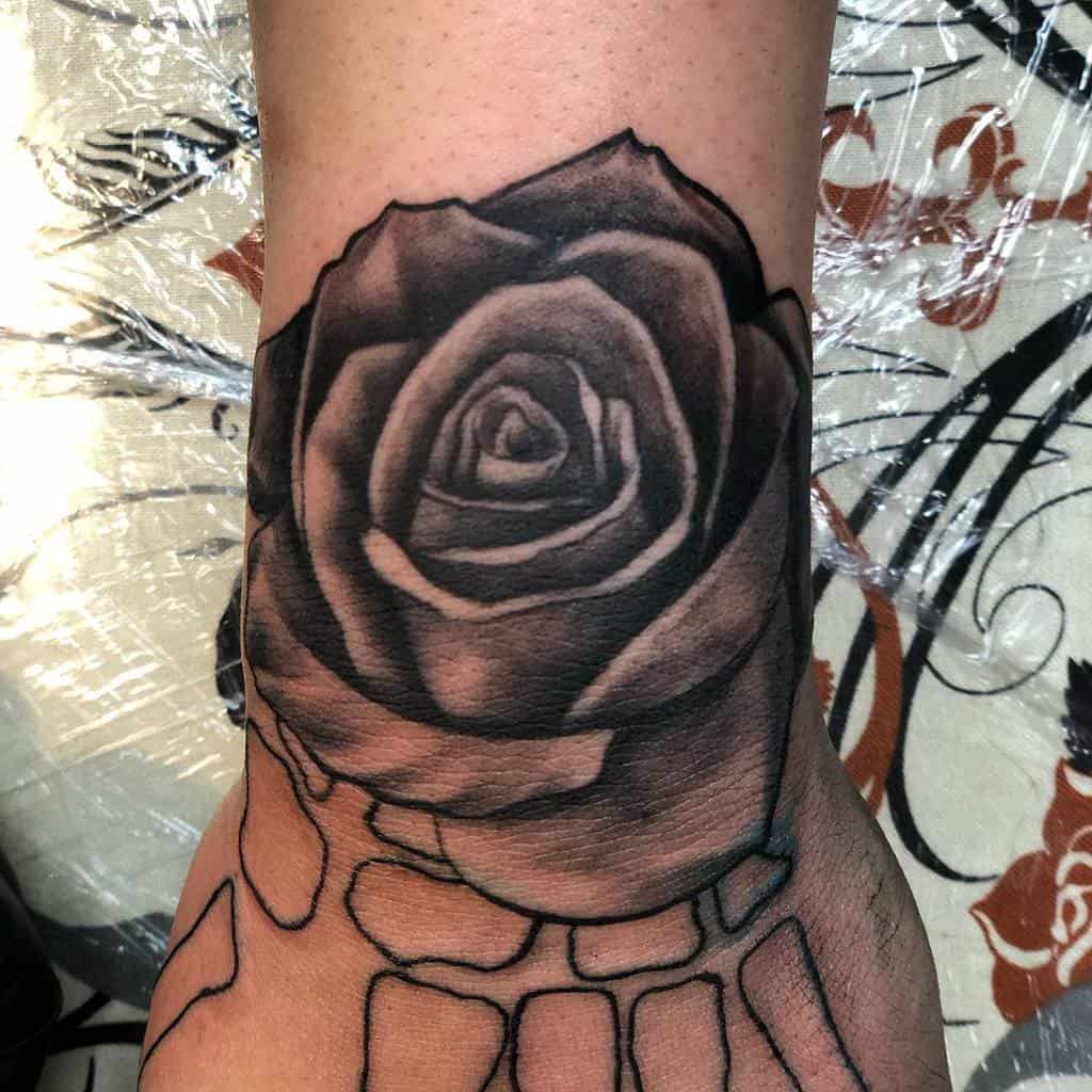 Black and gray rose tattoo on the back of a hand