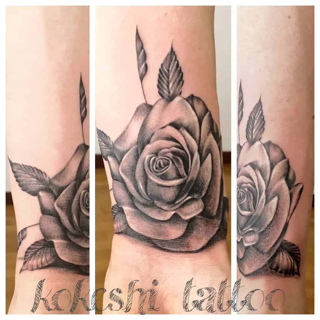 A stunning black and white rose tattoo blooms elegantly on the forearm