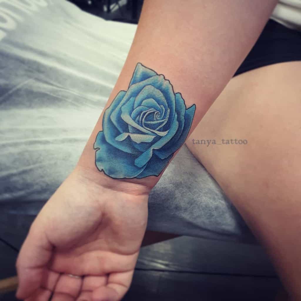 A realistic blue rose tattoo on a wrist